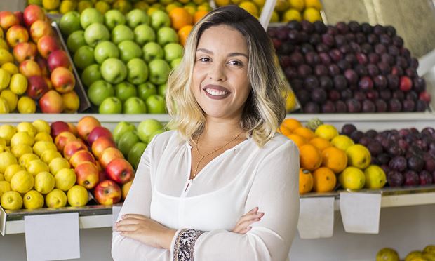 Retail dietitian standing in a grocery store next to fresh fruits and produce.