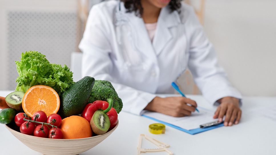 About RDNs photo of a practitioner writing in a file with a bowl of fruit in the background